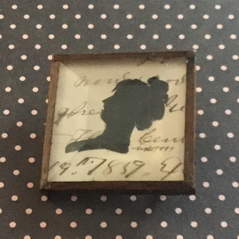 Silhouette pin with cameo on paper under glass